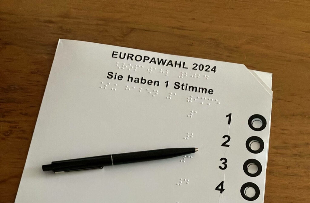 Wahlschablone für die Europawahl 2024: Kleines Kartonetui mit Löchern, welche in Braille und grossen Ziffern beschriftet sind. In diese kann man den Wahlzettel schieben und ihn auch bei Seh- oder Schreibbeeinträchtigungen autonom und gut markieren.