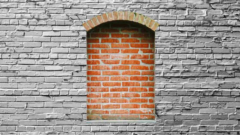 Orangefarben zugemauertes Fenster in weiss gestrichener Backsteinmauer