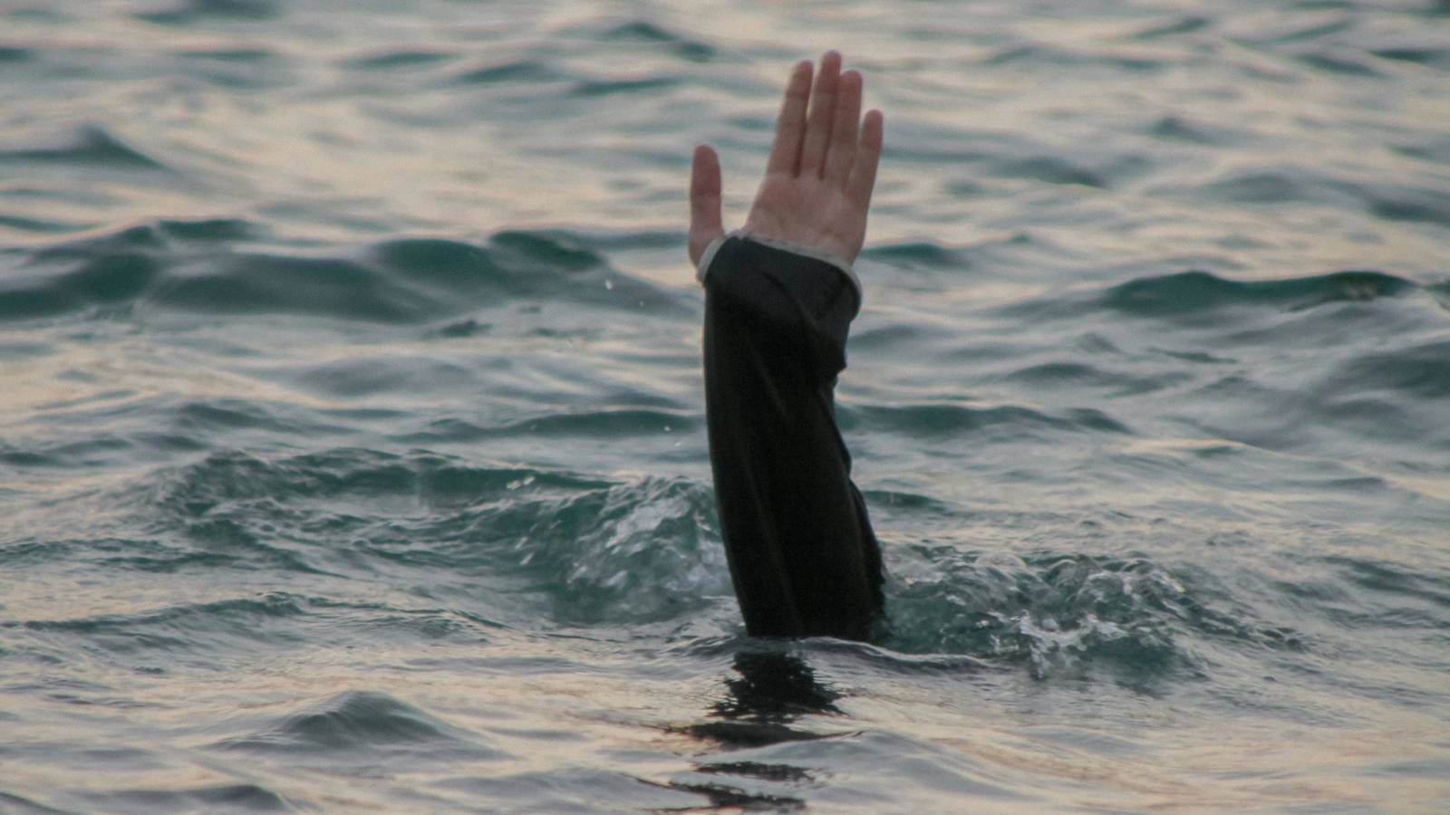 Eine Hand die aus dem Wasser winkt