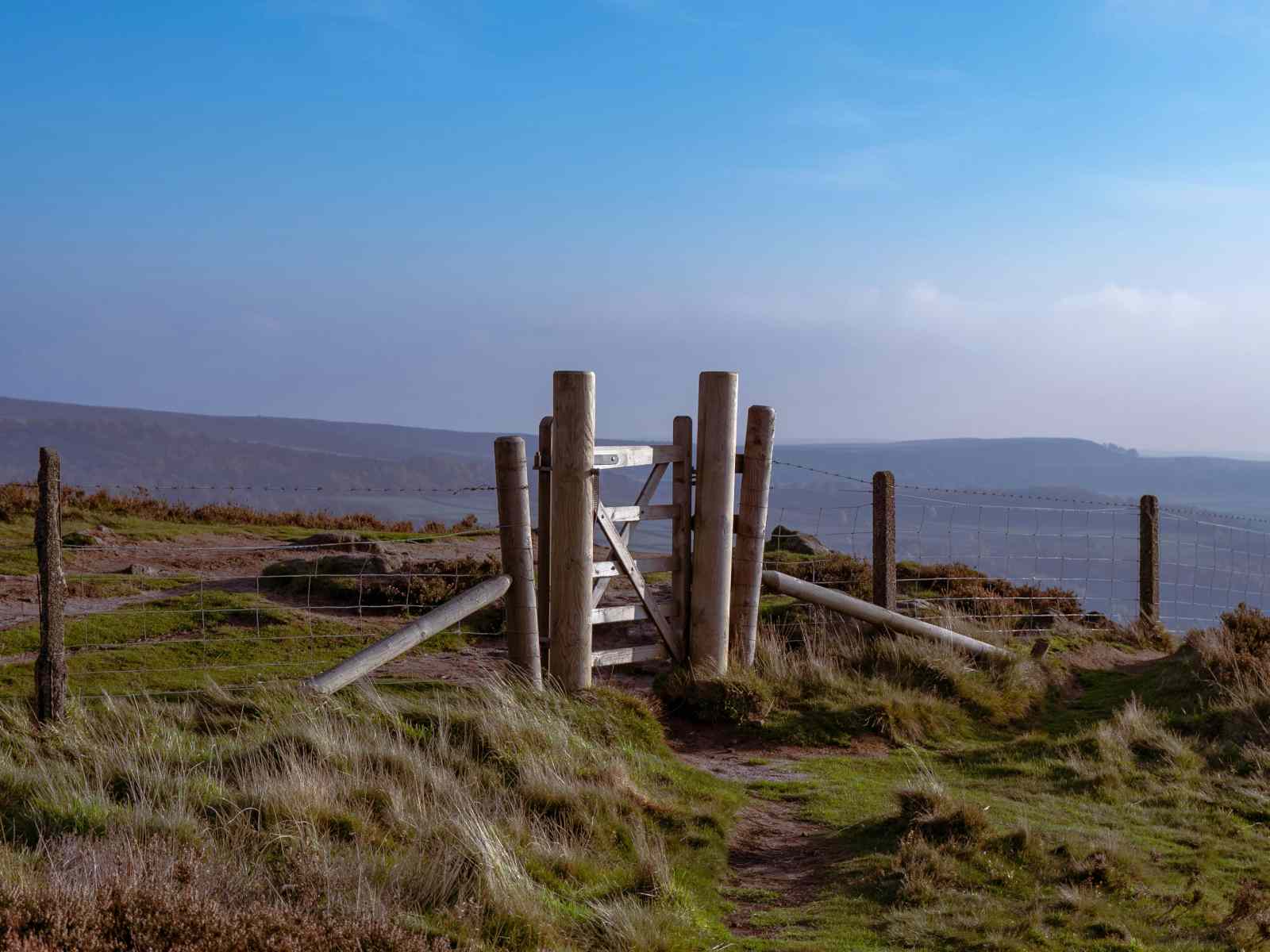Weidezaun mit Holztor vor blauem Himmel